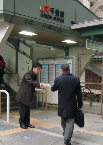 朝の駅立ちで県政報告を配布